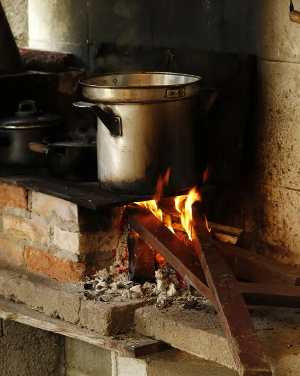 Fogão a lenha tradicional de tijolo com panelas e fogo aceso